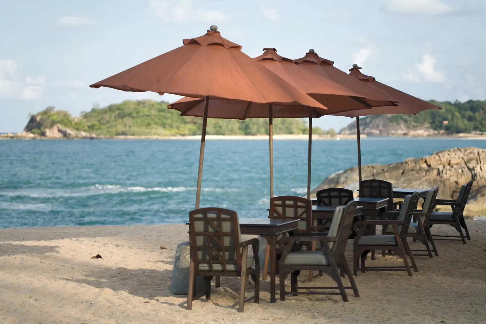 Tische und Sonnenschirme im Sand mit Blick aufs Meer, Hua Hin