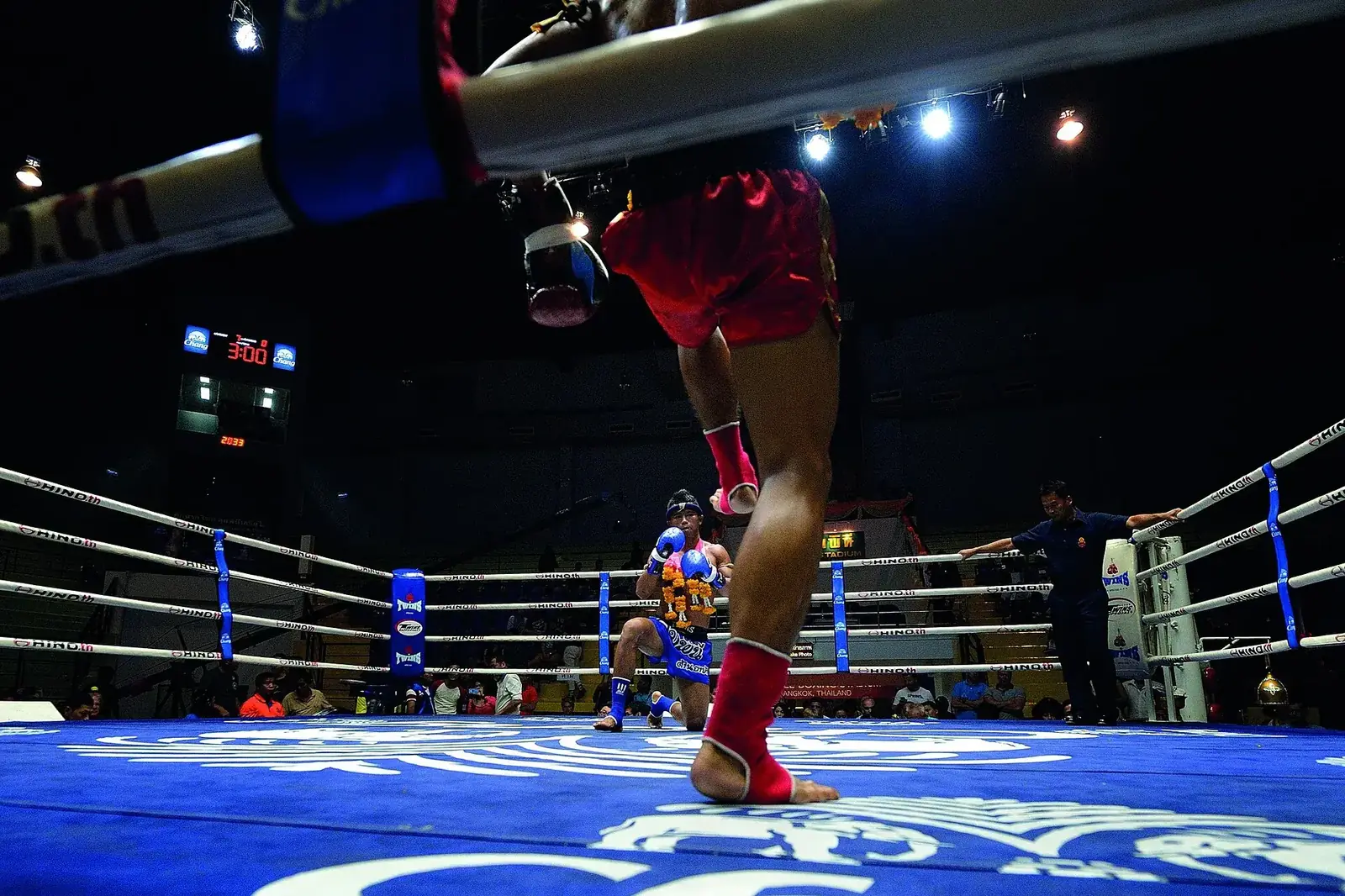 The Lumpinee ring on fight night: one boxer steps forward as his opponent kneels in salute